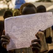 Child in South Sudan holds up map