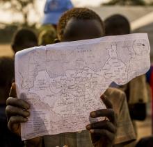 Child in South Sudan holds up map